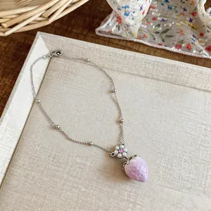 Close-up of pink strawberry pendant necklace with delicate flower pearl detail