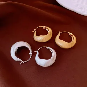 Close-up of 18K gold and silver plated brushed hoop earrings with textured finish