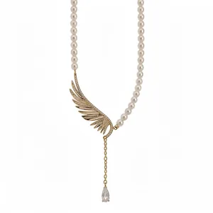 Elegant pearl necklace featuring a golden zircon-studded wing and teardrop pendant.