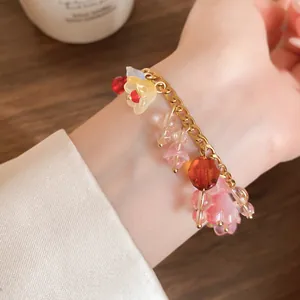 Detail van een roestvrijstalen armband met kleurrijke bloemenhangers van hars.