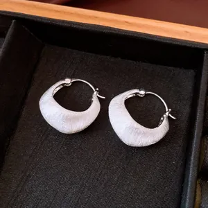 Macro detail of minimalist silver brushed texture hoop earrings with 18K gold plating finish