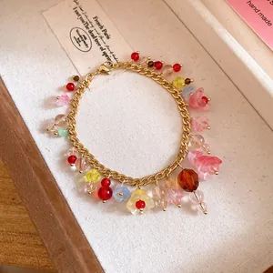 Detail van een kleurrijke harsbloem armband met goudkleurige roestvrijstalen ketting.