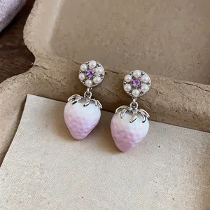 Close-up of sweet pink strawberry earrings with pearls and purple crystal detail