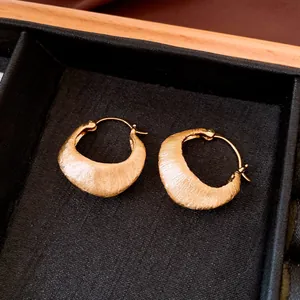 Close-up detail of high-end 18K gold-plated earrings with refined brushed texture.