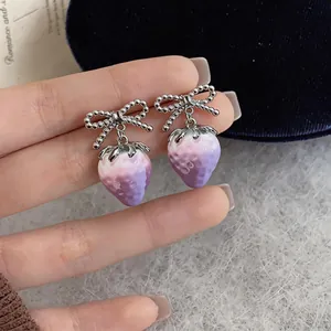 Detailed close-up of sweet strawberry drop earrings with silver bow and purple gradient