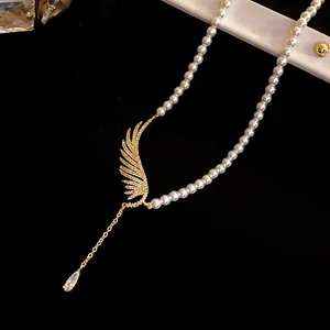 Close-up of elegant pearl necklace with zircon wing and drop pendant detail.
