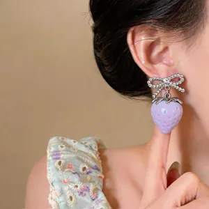 Close-up of a sweet purple strawberry drop earring with a sparkling rhinestone bow