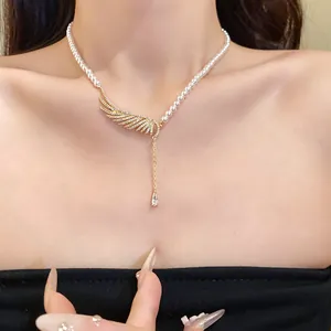 Close-up detail of a pearl necklace with a zircon-studded wing and waterdrop pendant