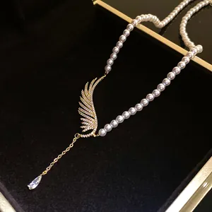 Detailed close-up showing the sparkling zircon wing and teardrop charms on a pearl necklace