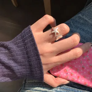 Nahaufnahme eines silbernen Seestern- und Muschel-Ring am Finger