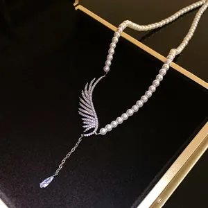 Macro detail of elegant zircon wing and pearl pendant necklace in luxury box
