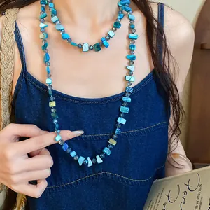 Close-up detail of a double-layered blue square shell and bead necklace worn by a model.