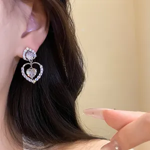 Détail en gros plan d'élégantes boucles d'oreilles pendantes double cœur en zircone