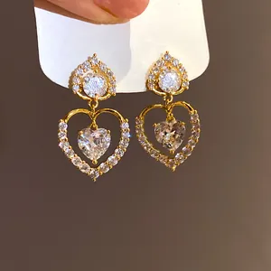 Gros plan de boucles d'oreilles pendantes en forme de cœur avec zircons étincelants.