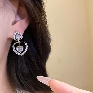 Détail de boucles d'oreilles pendantes double cœur en argent avec zircons étincelants.