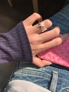 Lifestyle-Detailaufnahme eines silbernen Seestern- und Muschelrings an einem Finger