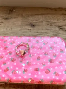Nahaufnahme eines silbernen Seestern- und Muschelrings auf rosa Erdbeermuster