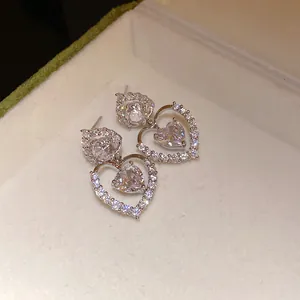 Gros plan de boucles d'oreilles cœur en argent avec zircone étincelante dans un écrin.