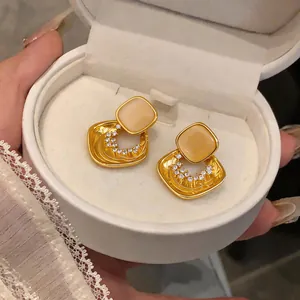 Dettaglio elegante di orecchini in oro di lusso con pietra occhio di gatto e zirconi.