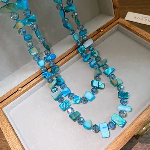 Close-up detail of blue square shell beads and faceted crystals in a wooden box