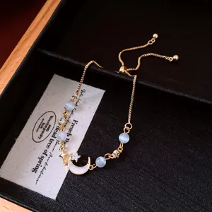 Detailed close-up of French retro gold moon bracelet with cat-eye beads and zircon stones