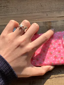 Detailaufnahme eines silbernen Seestern- und Muschelrings an einer Hand getragen