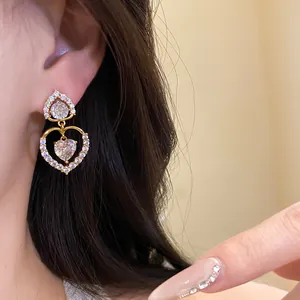 Vue détaillée d'élégantes boucles d'oreilles en zircon doré à double cœur sur l'oreille