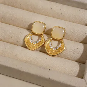 Primo piano di orecchini d'oro con pietre occhio di gatto gialle e accenti in zircone.