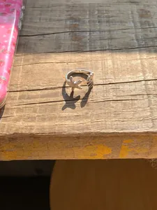 Nahaufnahme eines silbernen offenen Rings mit Seestern und Muschel auf einer Holzoberfläche