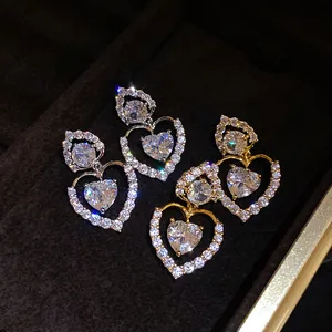 Gros plan de boucles d'oreilles pendantes en double cœur avec des zircons brillants