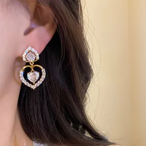 Gros plan détaillé de boucles d'oreilles pendantes à double cœur en zircone étincelantes sur l'oreille