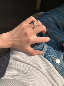 Nahaufnahme eines silbernen Seestern- und Muschelrings an einem Finger bei Sonnenlicht.