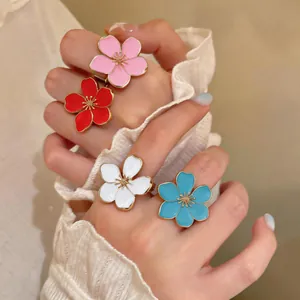 Detail of colorful enamel flower open rings on hand with ruffled sleeve accessories.
