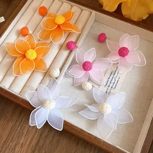 Detailed macro view of colorful mesh fabric flower earrings inside a wooden jewelry box