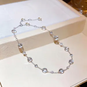 Elegante collana con perle di vetro trasparente e catena argentata su vassoio crema