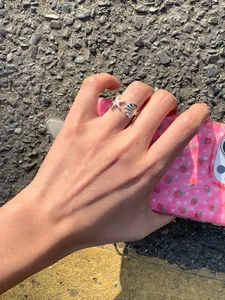 Detailansicht eines silbernen Seestern- und Muschelrings an einer Frauenhand.