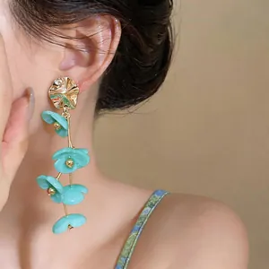 Close-up of turquoise acrylic flower tassel earrings with gold alloy studs for a sweet look
