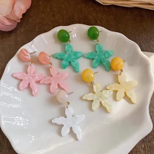 Primo piano di orecchini a stella marina in resina su un piatto a forma di conchiglia