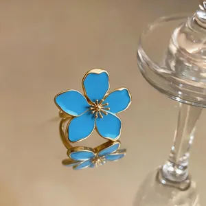Close-up of an elegant blue enamel flower ring with an adjustable golden metal band