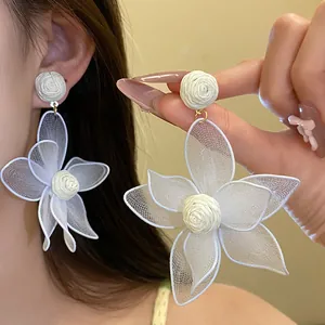 Close-up macro view of white mesh flower earrings featuring delicate woven center