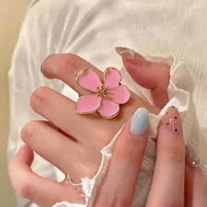 Close-up of elegant pink enamel flower open ring with gold trim on hand