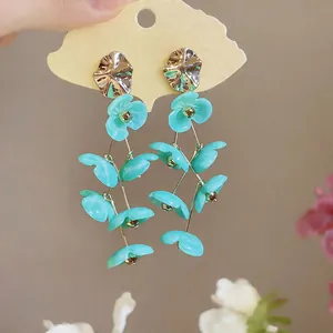 Detail of mint green acrylic flower tassel earrings with golden alloy studs and accents