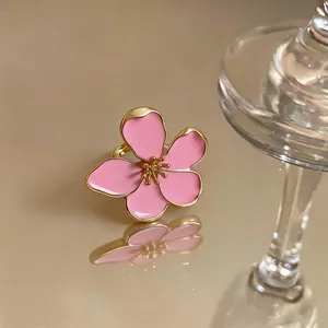 Close-up macro shot of a delicate pink enamel flower ring with golden metal edges