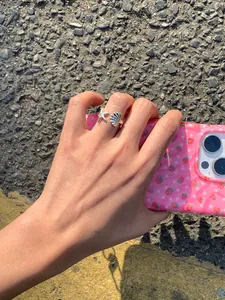 Nahaufnahme eines silbernen offenen Rings mit Seestern- und Muschel-Anhängern am Finger