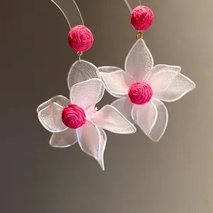 Macro view of sweet pink mesh flower earrings showing exquisite woven texture detail.
