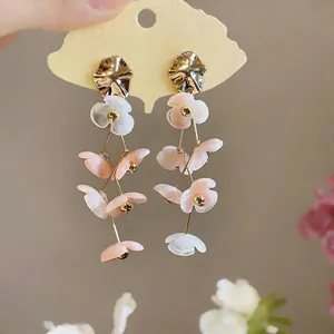 Close-up detail of stylish acrylic flower tassel earrings with gold-toned metal accents