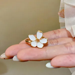 Close-up of elegant gold-plated flower ring with white enamel petals for women