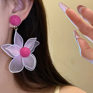 Macro detail of a sweet pink mesh flower earring worn on an ear with a delicate design