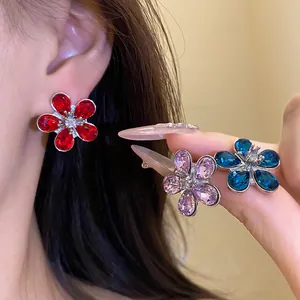 Macro detail showing vibrant crystal flower stud earrings in red pink and blue colors