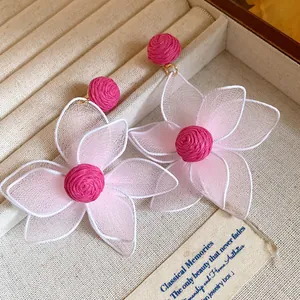 Close-up of pink mesh flower earrings with magenta centers in a jewelry tray